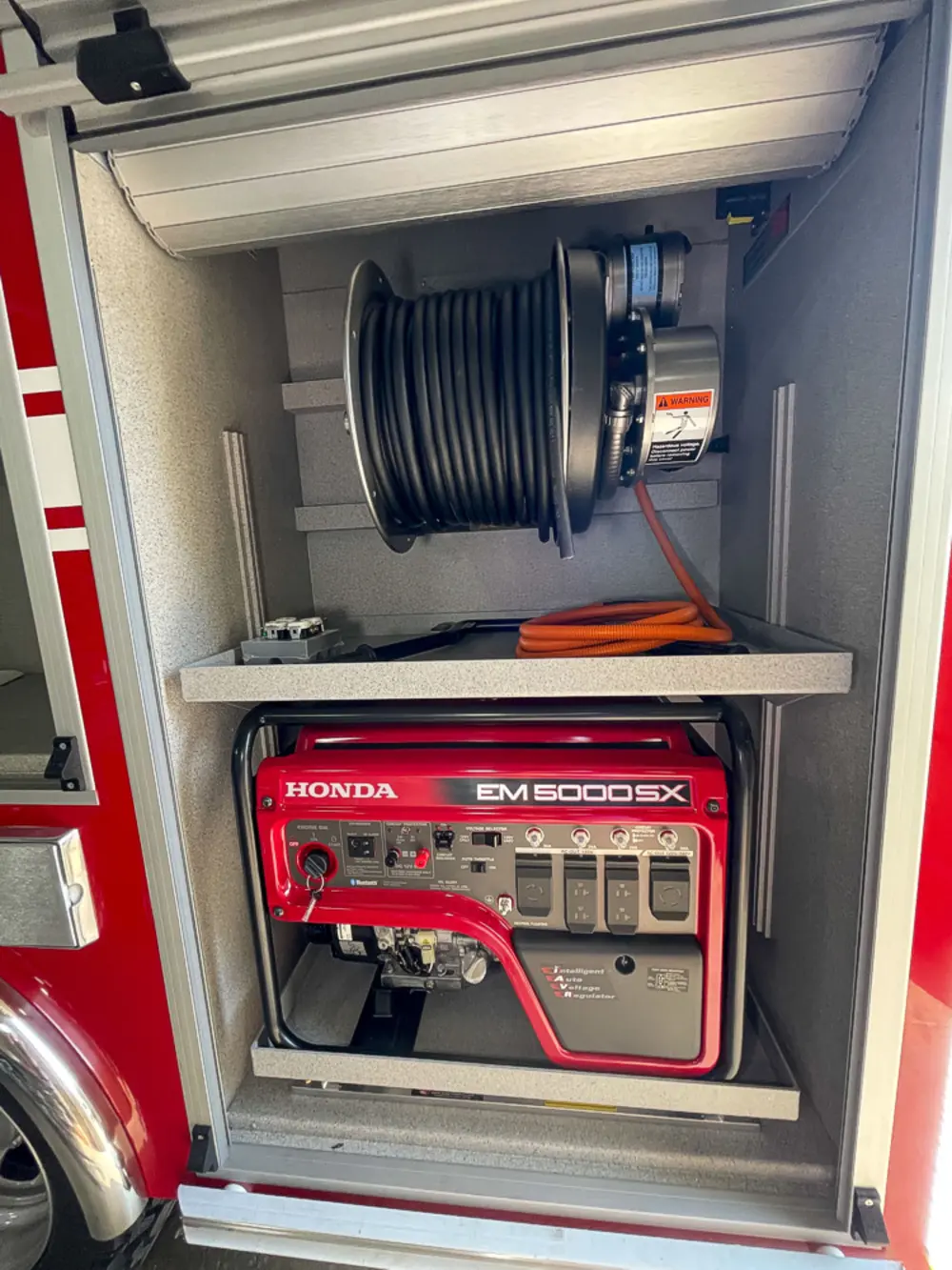 Exterior view of small fire truck showing cab, body compartments, and wheel/tire area.